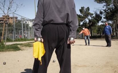 Un jugador sostiene sus bolas durante una partida de petanca en el parque de Aluche.