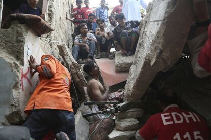Un grupo de voluntarios paquistaníes intenta rescatar a un hombre atrapado en Karachi (Pakistán).