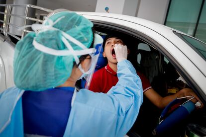 Un médico con material de protección extrae una muestra a un conductor para detectar la Covid-19 en un hospital de Bangkok.