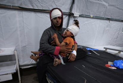 Una mujer herida sostiene a un niño en el hospital Ahli tras un bombardeo israelí contra una escuela donde se refugiaban personas desplazadas, en Ciudad de Gaza, en el norte de la Franja.