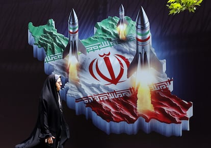 Una mujer iraní caminaba este lunes en Teherán junto a una pancarta antiisraelí con imágenes de misiles iraníes.