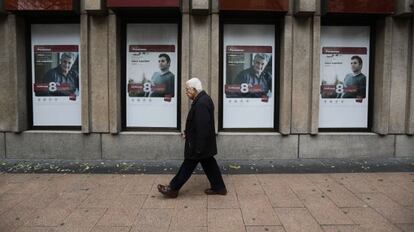 Un home passa per davant d'anuncis de plans de pensions d'un banc