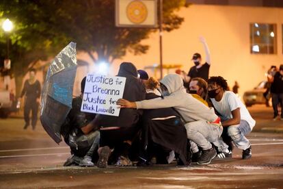 Um grupo de jovens se protege da policia durante os distúrbios em Mineápolis.