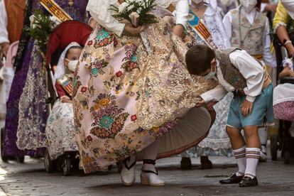 Un niño observa un traje tradicional de una fallera durante la Ofrenda a la Virgen. Un ambiente desangelado sin el aliento del público que habitualmente llena la plaza, sus aledaños y parte del recorrido.