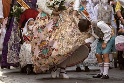 Un niño observa un traje tradicional de una fallera durante la Ofrenda a la Virgen. Un ambiente desangelado sin el aliento del público que habitualmente llena la plaza, sus aledaños y parte del recorrido.