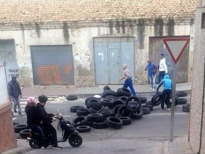 Un grupo de personas  levanta una barricada en la entrada del barrio melillense de la Ca&ntilde;ada. 