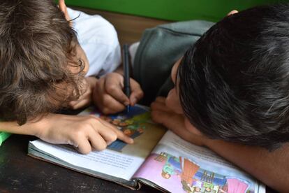 Dos niños leen un libro.