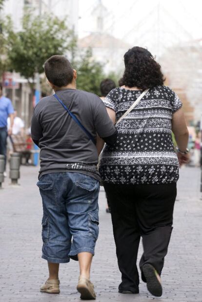 Una mujer pasea junto a un joven por una calle de Madrid.