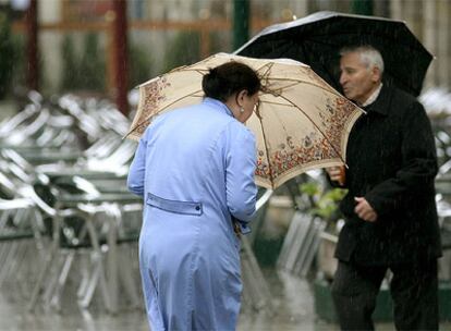 Dos transeúntes se protegen de la lluvia en la Plaza Mayor de Lugo