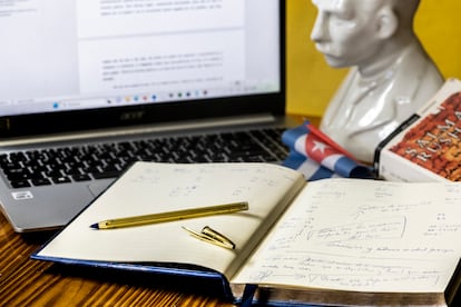 El escritorio de Elaine Vilar Madruga, con un pequeño busto de José Martí, una bandera de Cuba, un libro de Salman Rushdie y su cuaderno de notas. 