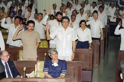 La presidenta electa Violeta Chamorro (sentada) observa la Asamblea Nacional juramentando en los miembros recientemente elegidos el 24 de abril de 1990 en Managua. Detrás de ella están el vicepresidente sandinista, Sergio Ramírez (derecha) y el presidente saliente de la Asamblea, Carlos Núñez (izquierda). 