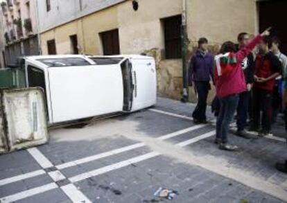 Grupos de jóvenes han volcado un vehículo en la Calle Eslava de Pamplona durante los incidentes ocurridos en el Casco Viejo con varios grupos de estudiantes tras la manifestación que ha recorrido las principales calles de la ciudad en la jornada de huelga convocada contra la LOMCE en todo el Estado.