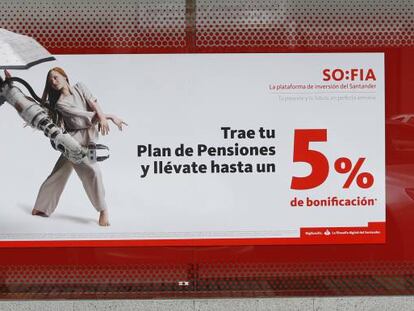 Una mujer pasa delante de un anuncio de planes de pensiones, en una oficina de Banco Santander, en Madrid.