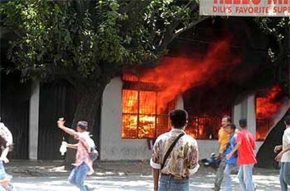 Varios manifestantes corren después de haber incendiado un supermercado propiedad de extranjeros.