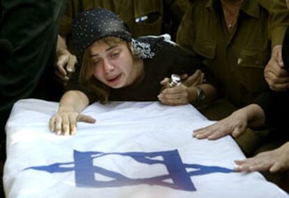 La viuda de un soldado israelí se abraza al ataúd donde yace su marido, muerto el martes.