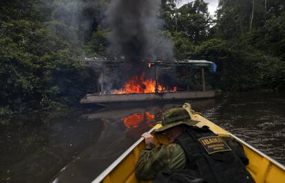 Un agente de la Agencia ambiental de Brasil, observa un ferry de minería incendiado a orillas del río Uraricoera.