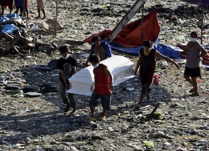 Cuatro hombres transportan un ataúd entre los cadáveres que han sido encontrados en varios lugares de la localidad filipina de Cayagan de Oro.