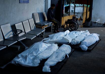 Un niño permanece sentado cerca de varios cadáveres en la morgue de un hospital en Rafah, este viernes. 