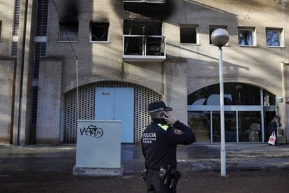 Un agente de la Guardia Urbana delante del edificio incendiado en la calle Marina. 