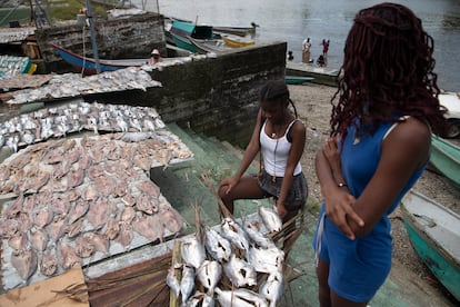 Dos jovenes organizan pescado para secarlo frente a la plaza de mercado.