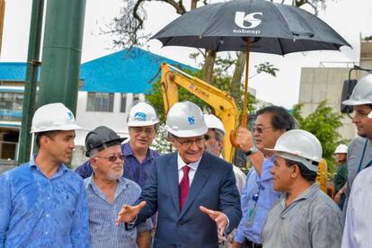 Massato segura um guarda-chuva durante um ato com o governador.