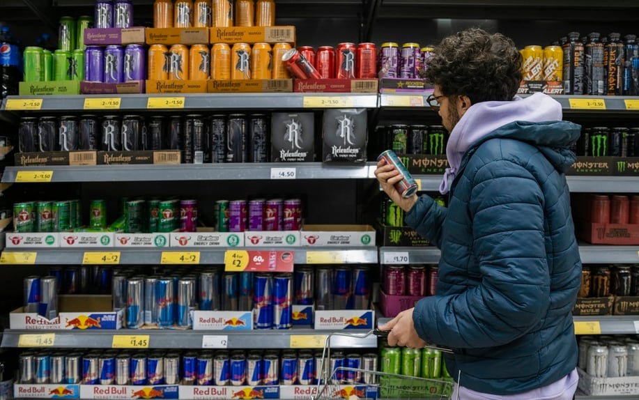 Un joven mira la sección de bebidas energéticas en el supermercado.