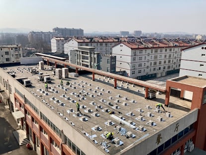 Un grupo de operarios trabaja en una instalación fotovoltaica sobre la azotea de un colegio del distrito de Zhangqiu, en Jinan.