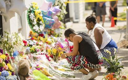 Diverses persones deixen flors al memorial aixecat per les nou víctimes.