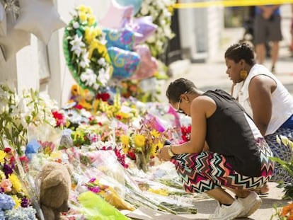 Diverses persones deixen flors al memorial aixecat per les nou víctimes.