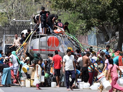 Habitantes de Nueva Delhi (India) hacen acopio de agua transportada por un camión cisterna durante una ola de calor a comienzos de junio.