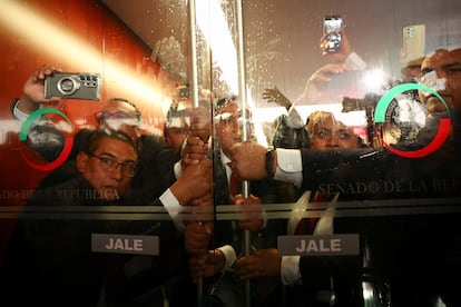 Personal de seguridad sostiene una puerta mientras los manifestantes recorren la sede del Senado.