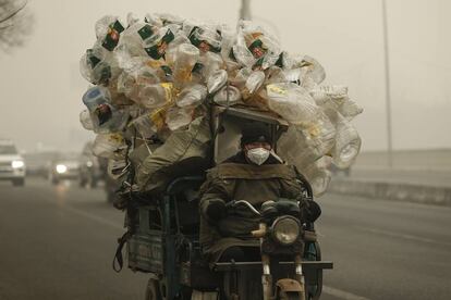 Un motorista conduce su motocarro por Shangháilleva repleto de botellas de plástico para ser recicladas.