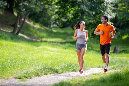 Una pareja joven corre por el campo.