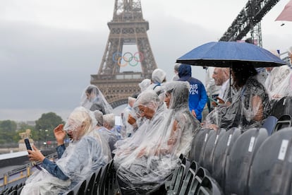 Varios espectadores se protegen de la lluvia minutos antes del comienzo de la ceremonia de inauguración de los Juegos Olímpicos de París, este viernes. 