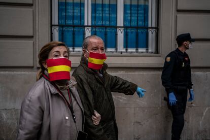 Una pareja con una mascarilla casera que reproduce la bandera de España, durante las protestas en contra del Gobierno que se produjeron en la calle Núñez de Balboa. OLMO CALVO