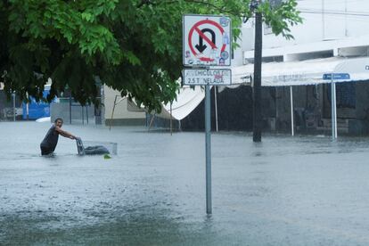 Un hombre empuja un carro de supermercado en una calle inundada tras el paso de Helene, este miércoles en Cancún.