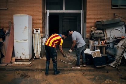 Varios vecinas limpian una vivienda de Benetússer (Valencia) afectada por la riada, el lunes.