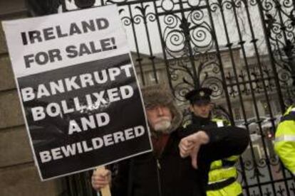 Un hombre porta una pancarta durante una manifestación en contra de los Presupuestos Generales ante el Parlamento irlandés en Dublín (Irlanda). EFE/Archivo