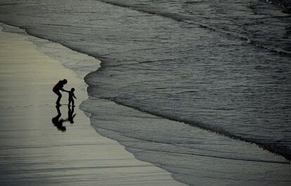 Una mujer y un niño juegan en la playa de Los Quebrantos, que junto con el playón de Bayas o del Sablón, en el vecino concejo de Castrillón, forman un arenal de más de 3 km de longitud.