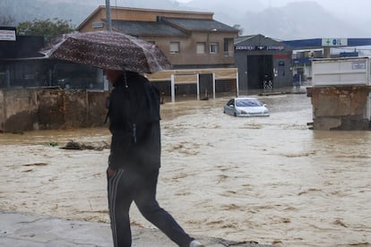 Un hombre pasa por una zona inundada en la carretera de Caravaca en Lorca (Murcia), este jueves.