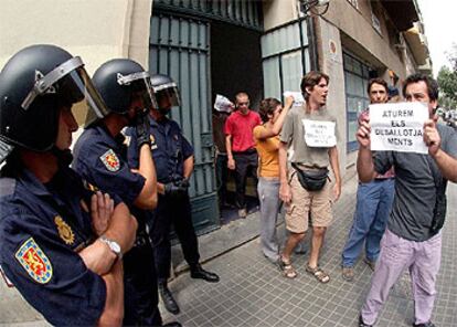 Varios <i>okupas</i> abandonan la sede del PSC, llevando carteles, después de la llegada de la policía.

 / EFE