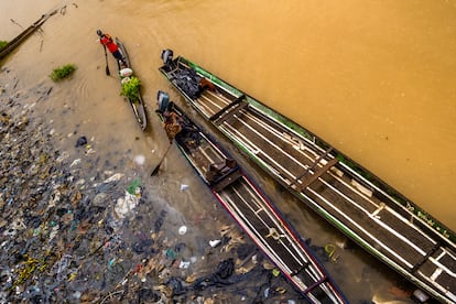 Hombres navegan junto a un montón de basura en el río Atrato, en Quibdó, en 2019.