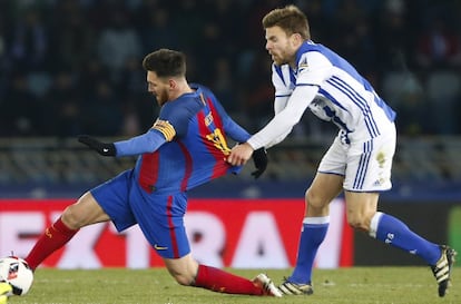 El centrocampista de la Real Sociedad, Asier Illarramendi (d), sujeta al delantero argentino del F. C. Barcelona, Leo Messi.