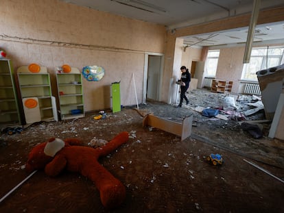 An employee picks up some objects inside a kindergarten damaged during Russian drone strikes on Saturday in Kiev, Ukraine.