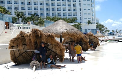 La gente se protege del sol en cabañas derribadas por fuertes vientos, antes de la llegada del huracán 'Beryl', en Cancún, México.