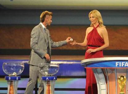 David Beckham entrega una bola a Charlize Theron, presentadora del acto; abajo, a la derecha, el trofeo de campeón del mundo.