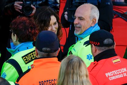 La presidenta de la Comunidad de Madrid, Isabel Díaz Ayuso (centro), saluda a miembros de Protección Civil y Emergencias Madrid, este lunes en la Puerta del Sol. 