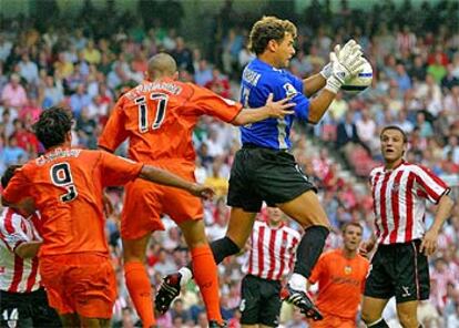 El portero del Athletic, Aranzubia, se adelanta a los jugadores del Valencia Corradi y D. Navarro para blocar el balón.