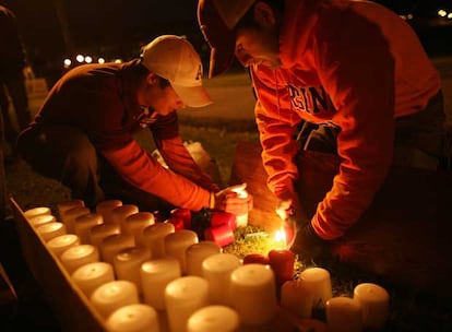 Dos estudiantes encienden velas en la vigilia que se ha organizado por la tarde para recordar a las víctimas del tiroteo.