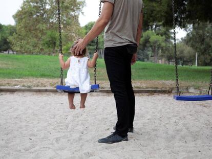 Un hombre juega con una niña en un columpio en Valencia. 